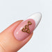 Gold plated four hearts nail charm on a pink and white French almond nail, NSI Australia