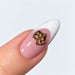 Gold plated theatre masks nail charm on a pink and white French almond nail, NSI Australia