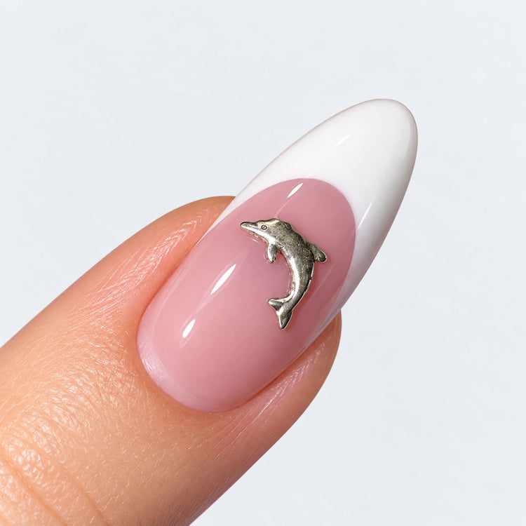 Silver tone small dolphin nail charm on a pink and white French almond nail, NSI Australia