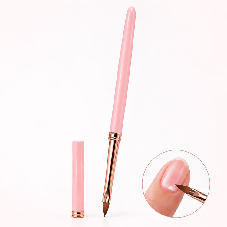 Pink pointed gel nail brush with rose gold ferrule and matching cap, shown applying gel near the cuticle of a natural nail.
