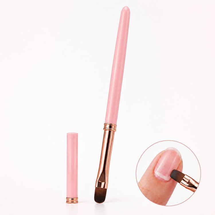 Pink gel nail brush with rounded tip, rose gold ferrule and matching cap, shown applying gel to a natural nail.

