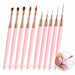 Set of 10 pink gel and ultra-fine liner nail brushes with rose gold ferrules, shown painting black curves on a nude pink nail.