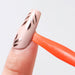 Orange nail suction cup stick holding a decorated false nail tip for easy nail art practice, gel polish application and manicure display work