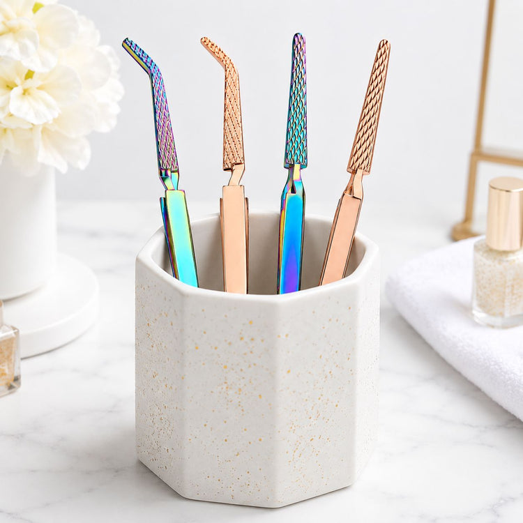 Rainbow and rose gold multi-function nail tweezers with textured grip displayed in a ceramic salon tool holder