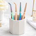 Rainbow and rose gold multi-function nail tweezers with textured grip displayed in a ceramic salon tool holder