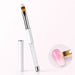 White ombré gel brush with feathered bristles, crystal-filled handle and matching cap, shown blending pink and white on a nail.
