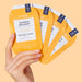 Hand holding VOESH New York Pedi in a Box Mango Delight deluxe 4-step pedicure kit sachets