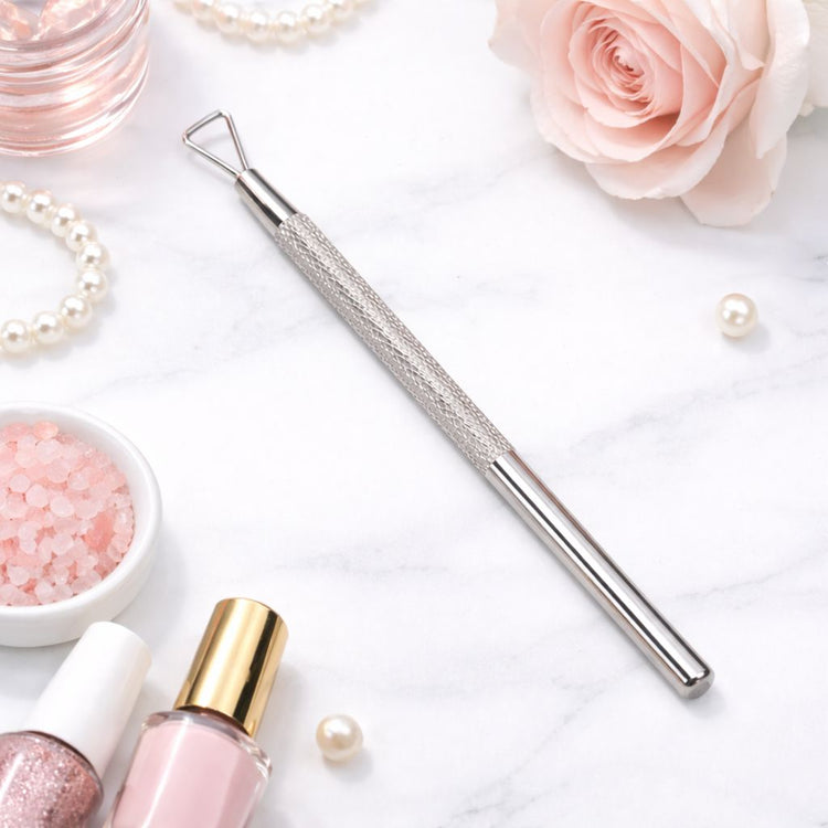 Stainless steel gel polish remover peeler scraper tool on marble background with nail polish and rose