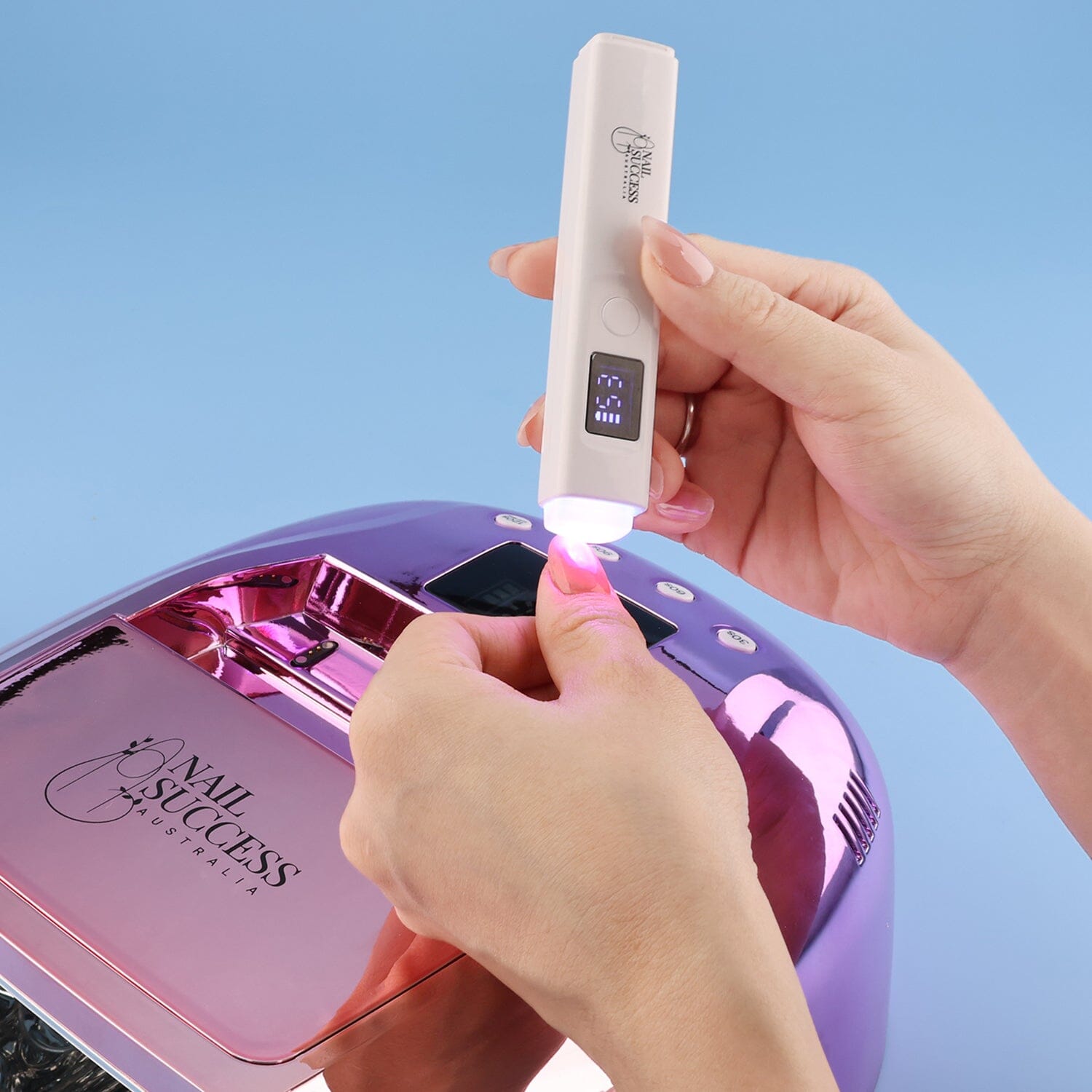 UV flash torch curing gel polish on thumb, white rechargeable nail lamp in use (rose gold unit)