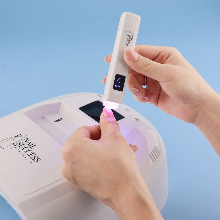 UV flash torch curing gel polish on thumb, portable rechargeable nail lamp in use