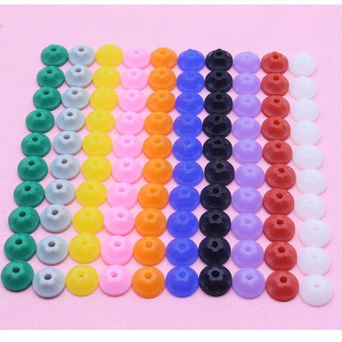 Mixed colour nail drill bit dust protector caps arranged in rows on a pink background, assorted silicone caps for e-file bits to help reduce dust entry and protect manicure drill handpieces