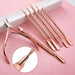 Rose gold nail tool set with cuticle nipper and five stainless steel manicure tools on pink background