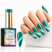 A hand with long, manicured nails painted in a shimmering teal-green magnetic nail polish is shown beside the bottle of Nail Success Diamond Gel Nail Polish, shade 23 Sapphire Surge.