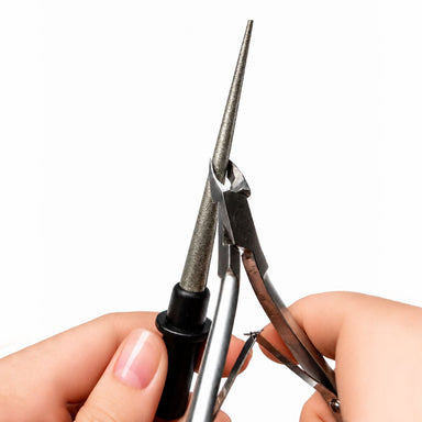 Nail tool sharpening file being used to sharpen manicure cuticle nippers, with tapered silver sharpening rod for maintaining sharp precision nail tools