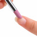Close-up of a pink stone cuticle nail file gently buffing the surface of a natural fingernail