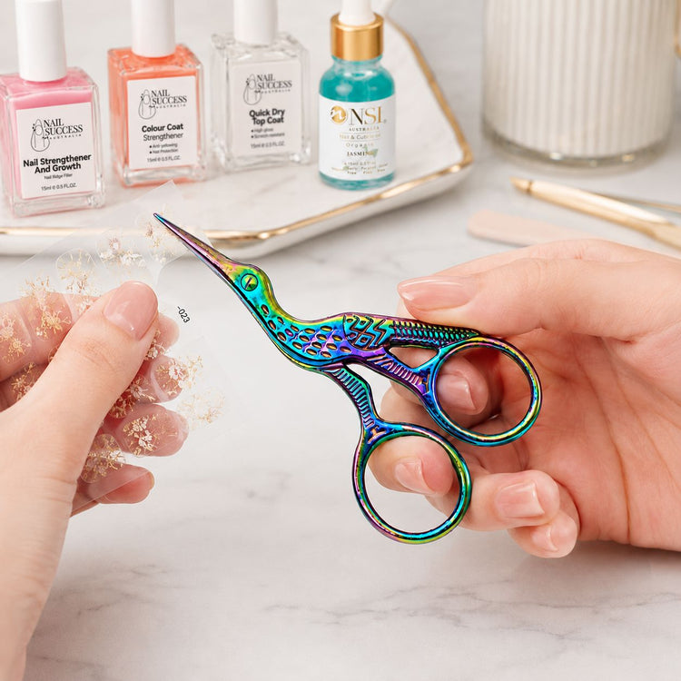 Rainbow stork nail scissors used to trim nail art stickers with NSI manicure products in background, NSI Australia