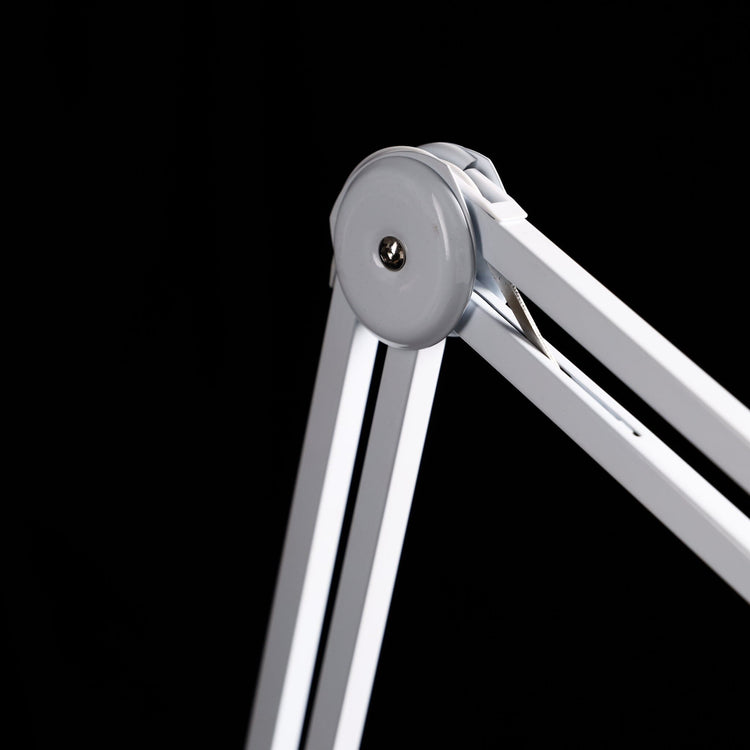 Nail Success Australia StudioFlex nail desk lamp — close-up of adjustable arm joint with tension spring, white hinge on black background