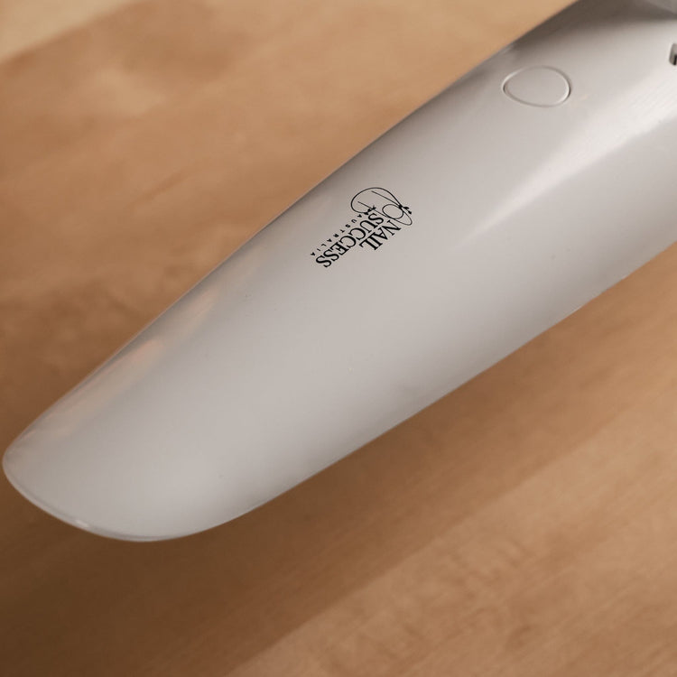 Nail Success Australia StudioFlex nail desk lamp — close-up of slim white LED panel with touch button and logo on wooden desk