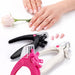 Pink, white, and black nail tip cutters with adjustable cutting guides beside finished French tip nails