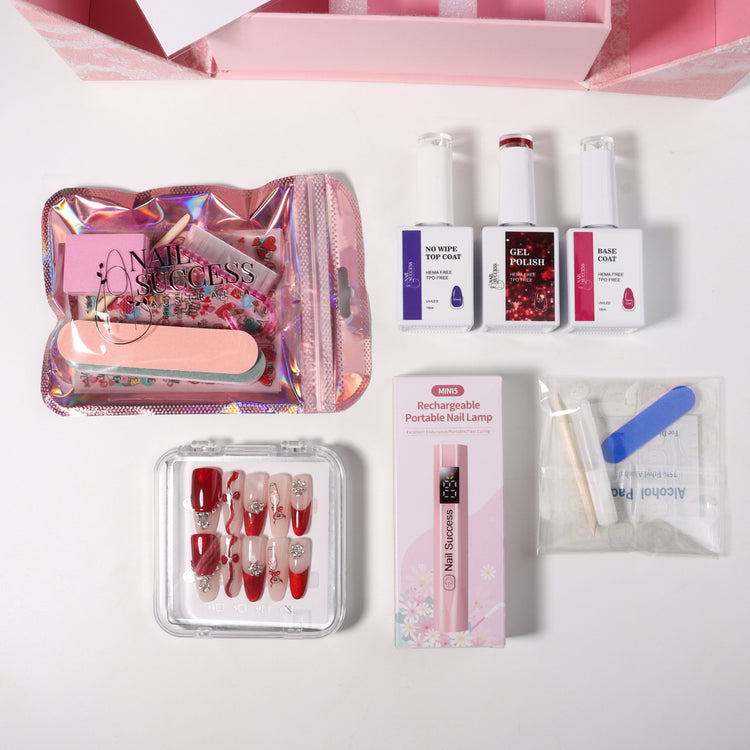 Valentine’s nail gift set flat lay with Nail Success Australia gel polish, base coat, no-wipe top coat, mini rechargeable nail lamp, tools and red press-on nails