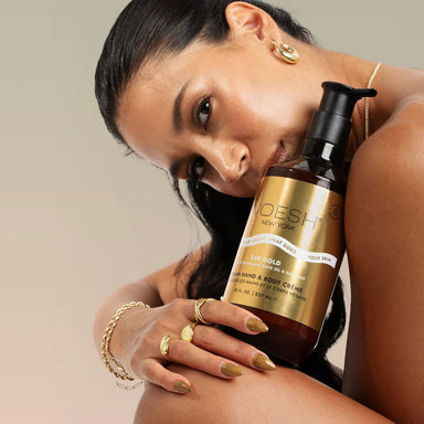 Model holding Voesh 24K Gold vegan hand and body crème bottle