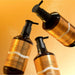 Voesh 24K Gold vegan hand and body crème pump bottles on gold background
